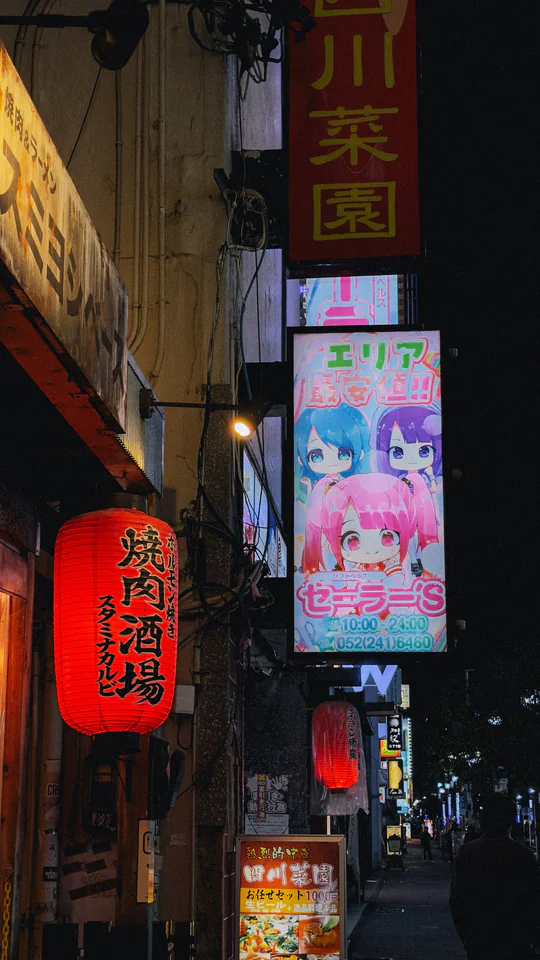 Colorful night street scene in Japan featuring bright neon signs and lanterns.