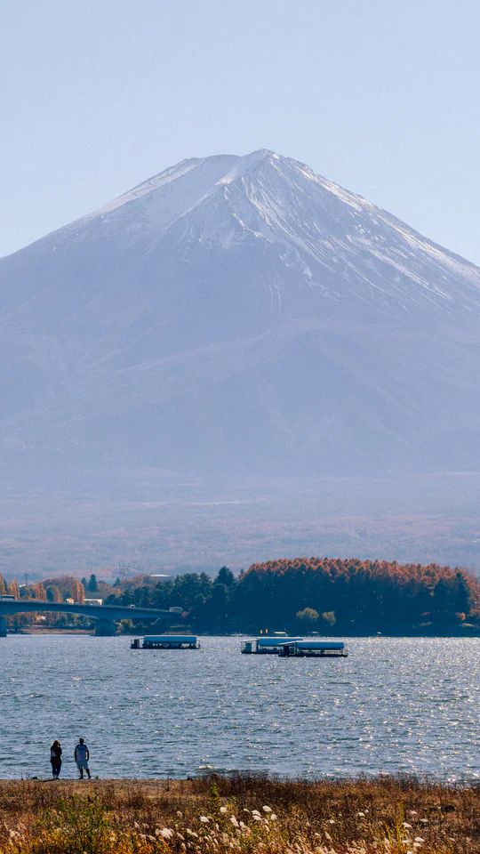 A serene autumn scene of Mount Fuji with boats on Lake Kawaguchi, capturing Japan's natural beauty.