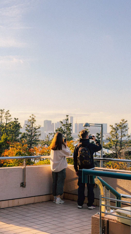 A couple stands on a terrace enjoying the scenic skyline of a Japanese city.