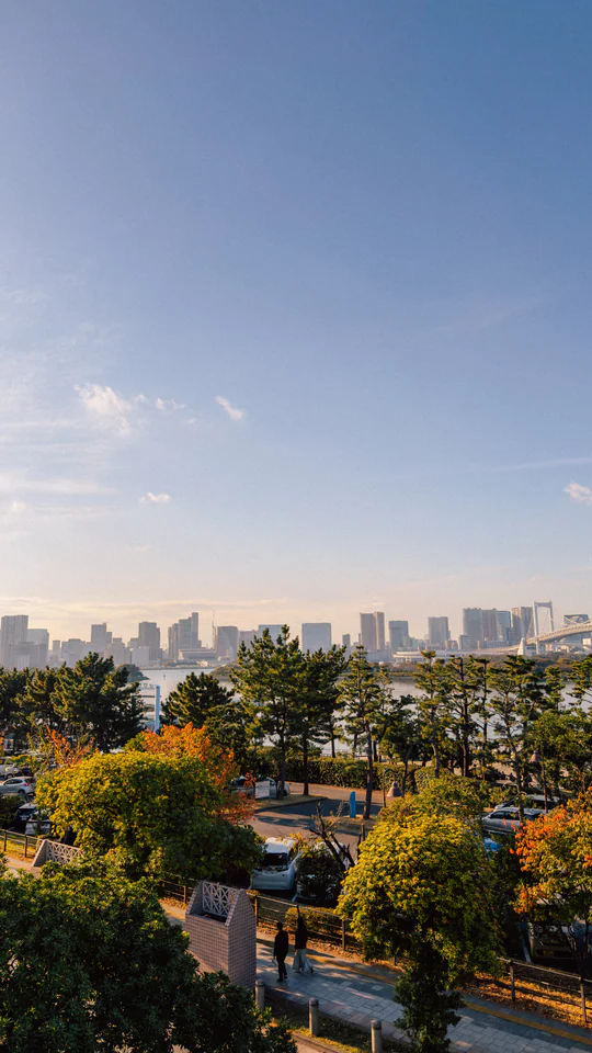 A stunning view of Tokyo's skyline framed by vibrant autumn trees under a clear blue sky.