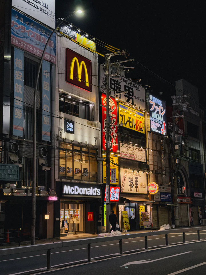 Illuminated Tokyo street at night showcasing vibrant signs and a McDonald's restaurant.