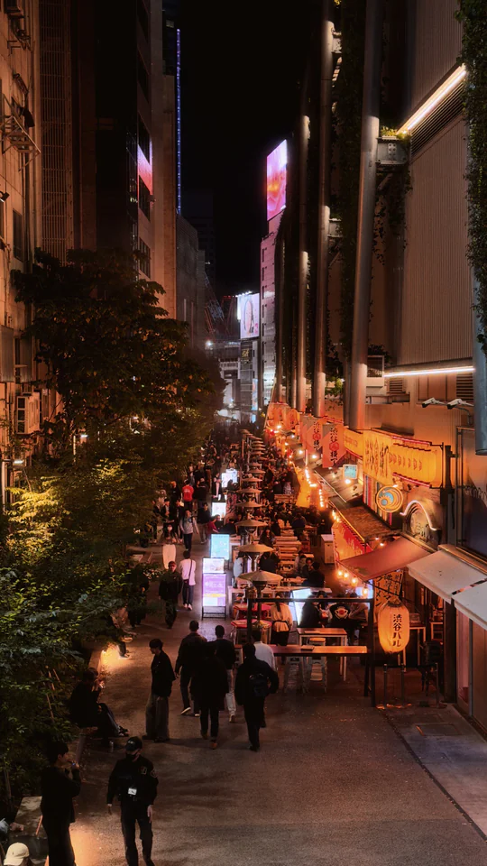 Discover Tokyo's bustling nightlife with crowds and neon lights in a lively Japanese alleyway.